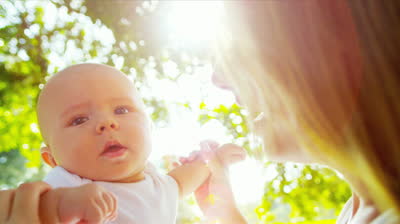 stock-footage-loving-young-caucasian-mother-holding-up-happy-baby-son-in-sunshine-outdoors-sun-lens-flare-shot-on